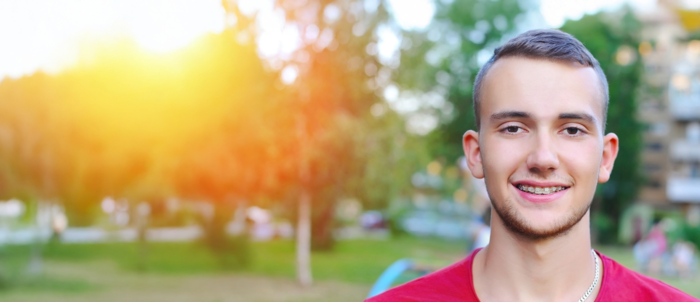 Young man with ceramic braces smiling after seeing an emergency orthodontist in Round Rock