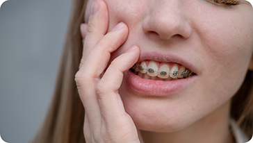 Girl with braces holding her cheek in pain