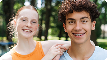 Teenage boy with braces smiling with a teenage girl without braces