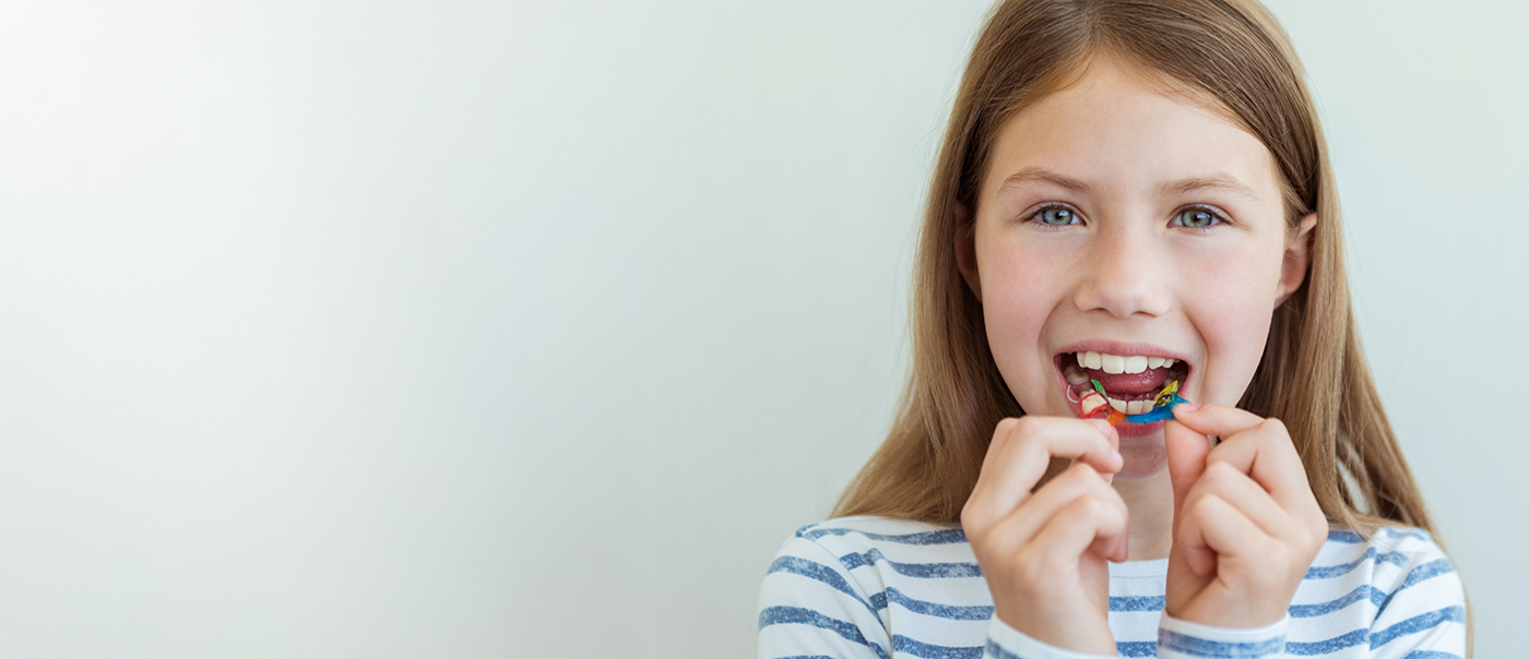 Young girl placing an orthodontic appliance over her teeth