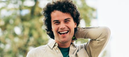 Man with curly brown hair smiling outdoors
