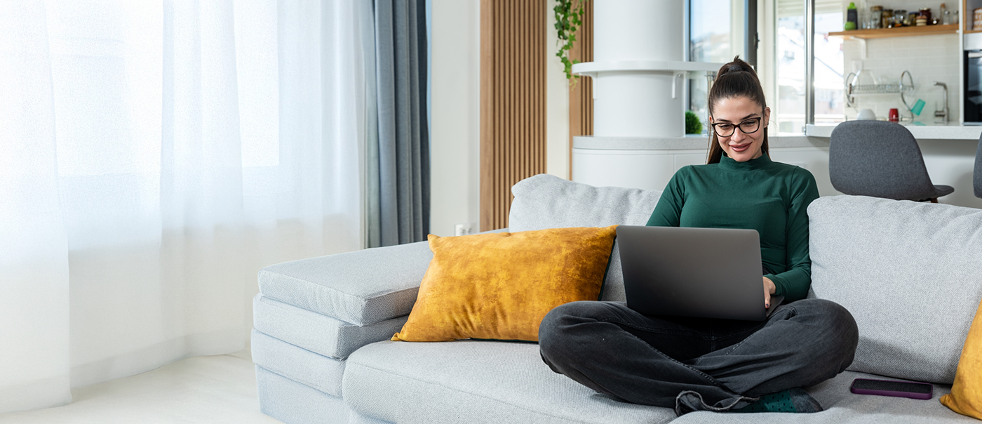Woamn sitting on a couch and using a laptop